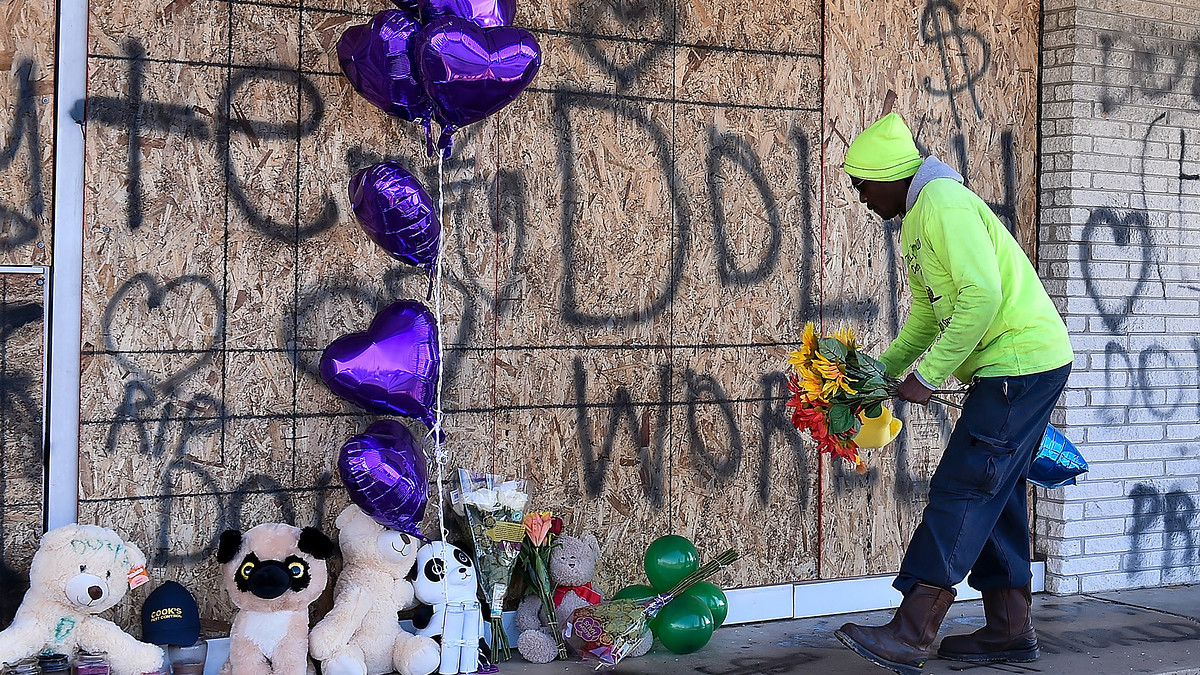 A man places flowers at the memorial for Young Dolph outside of Makeda's Cookies bakery