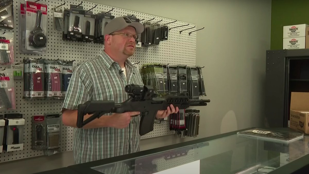 gun store owner holding weapon