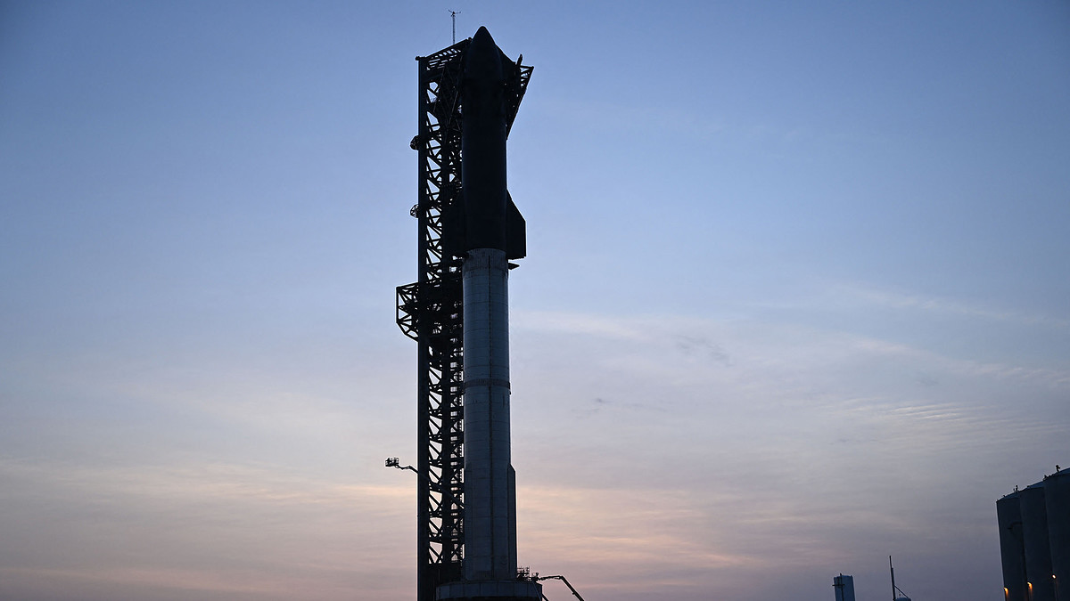 Workers in a lift prepare the SpaceX Starship after sunset
