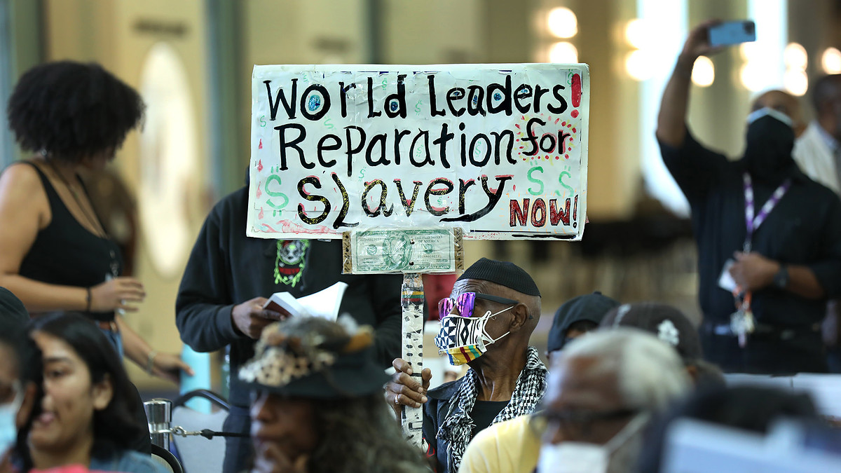 Los Angeles long time resident, Walter Foster, age 80, holds up a sign as the Reparations Task Force meets