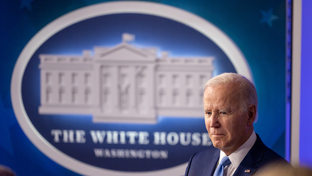 Biden is seen in front of a White House logo