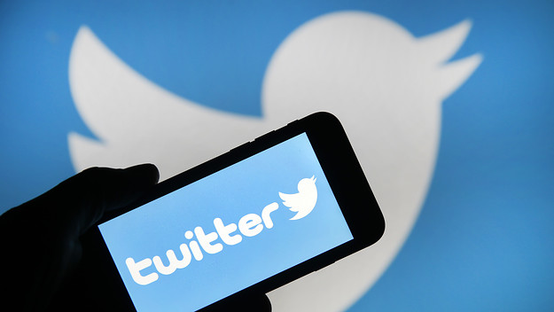 Twitter on a phone with the logo behind