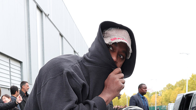 Kanye in a hoodie hiding half his face