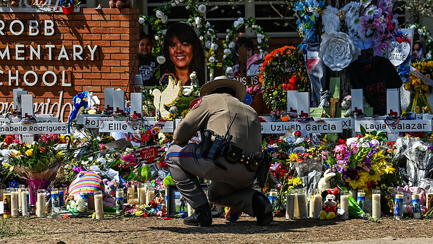 An officer pictured in front of makeshift memorial at Robb Elementary School.