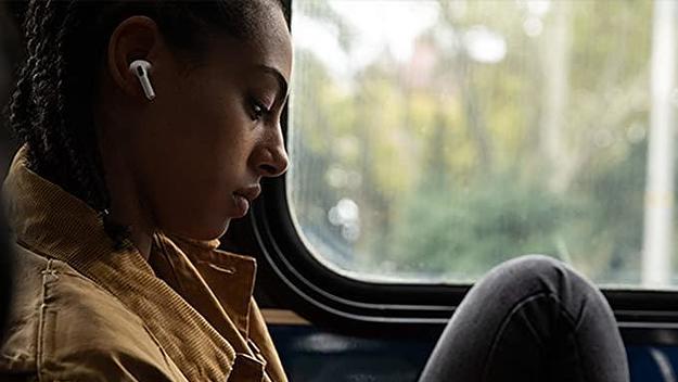 A woman looks at her iPhone while using her Apple AirPods.