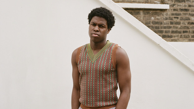 Daniel Caesar wearing a green and orange sweater vest