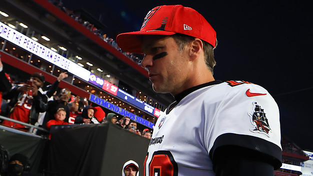 Tom Brady walks off the field after losing in the playoffs.