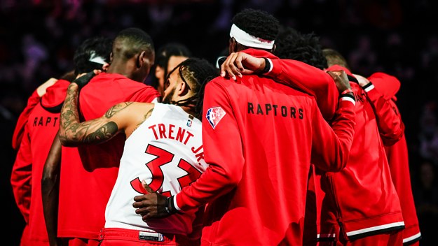 Gary Trent Jr and Pascal Siakam and other Toronto Raptors join in group huddle.