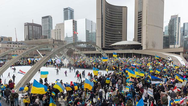 Demonstrators with yellow and blue Ukraine flags and anti-war signs in Downtown Nathan Phillips Square