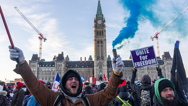 Protestors on parliament hill with signs and smoke flares