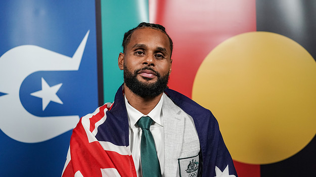 Patty Mills posing with Australian, Torres Strait Islands and Australian Indigenous flags