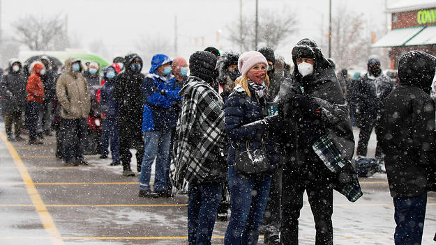 People wearing face masks line up to pick up free COVID-19 antigen rapid test kits in Mississauga