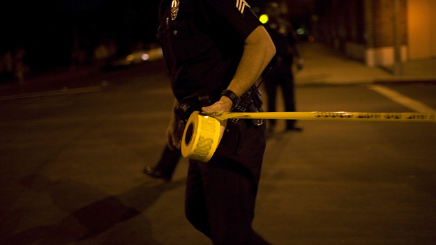 Police officer puts up tape at crime scene