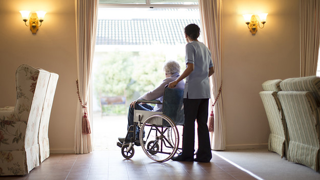 Nurse pushing patient in wheelchair at nursing home