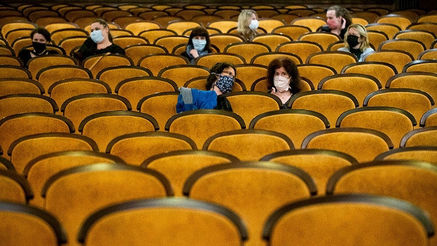 Attendees sitting in theater during pandemic.