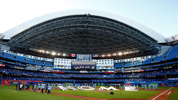 The Toronto Blue Jays line up behind a 'Home' sign to commemorate their first home game in Toronto this season prior to a MLB game against the Kansas City Royals at Rogers Centre on July 30, 2021 in Toronto, Canada.