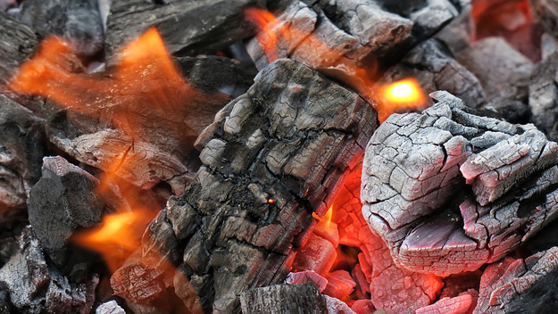 Charcoal burns and glows in a charcoal grill.