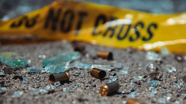 Bullet casings surround caution tape.