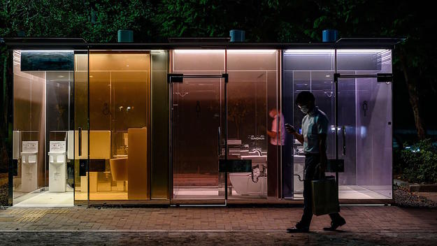 A man walks past a transparent toilet designed by Shigeru Ban.