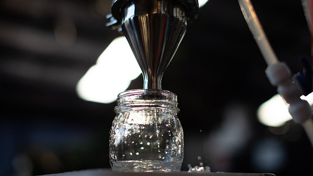 Spirit is transferred from the still into a container at One Drop Brewing.