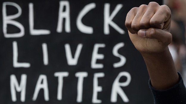 A demonstrator raises the fist next to a placard in Nantes