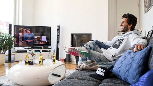 The wax figure of the actor Elyas M'Barek is shown in a scene on a couch while watching television