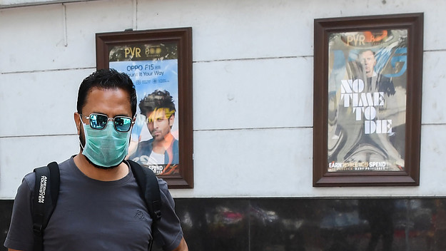A man wearing a facemask walks pasts the closed Rivoli cinema complex in New Delhi
