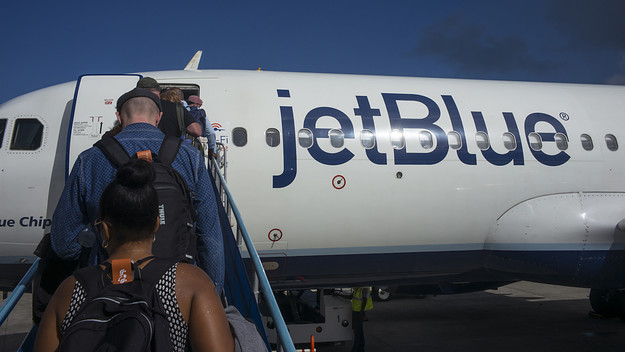 Passengers departing on a JetBlue Airways flight to New York walk up a ramp.