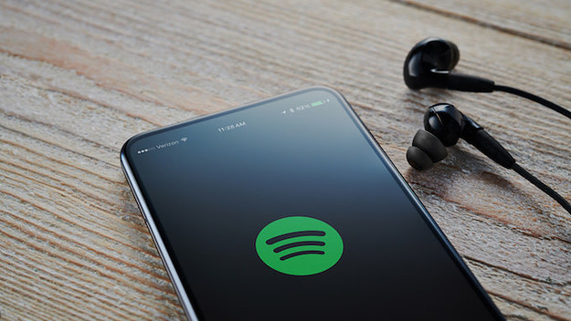 An Android smartphone with the Spotify Music logo visible on screen.