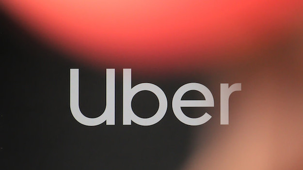 A man stands in front of a logo of Uber during launch of a campaign ParksNotParking.