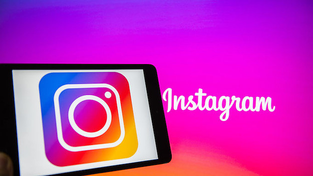 A man holds an Apple iPad Mini as he uses Instagram app.