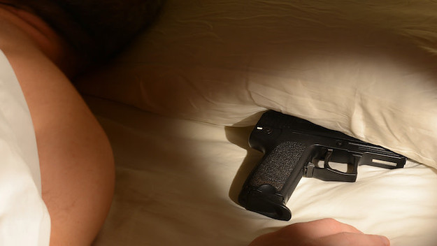Man in bed with gun underneath pillow.