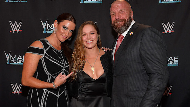 Stephanie McMahon, Ronda Rousey, and Triple H appear on the red carpet.