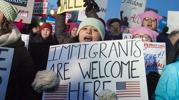 Woman holding 'Immigrants Are Welcome Here' sign.