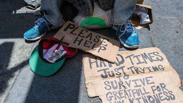 Homeless person begs along a sidewalk in downtown San Francisco