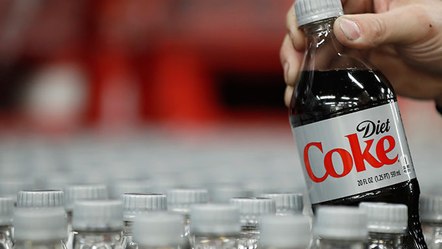 Someone with slightly grubby hands picking up a bottle of coke