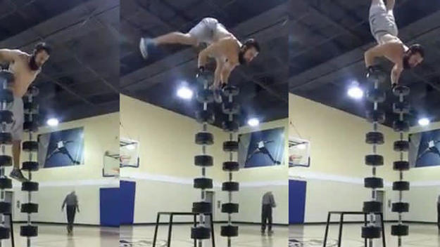 A gym rat piles dumbbells nine high so he can do handstand pushups on them.