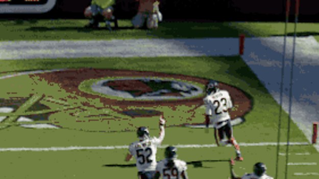 Football players in white jerseys celebrate a touchdown in an end zone with a logo on the grass.