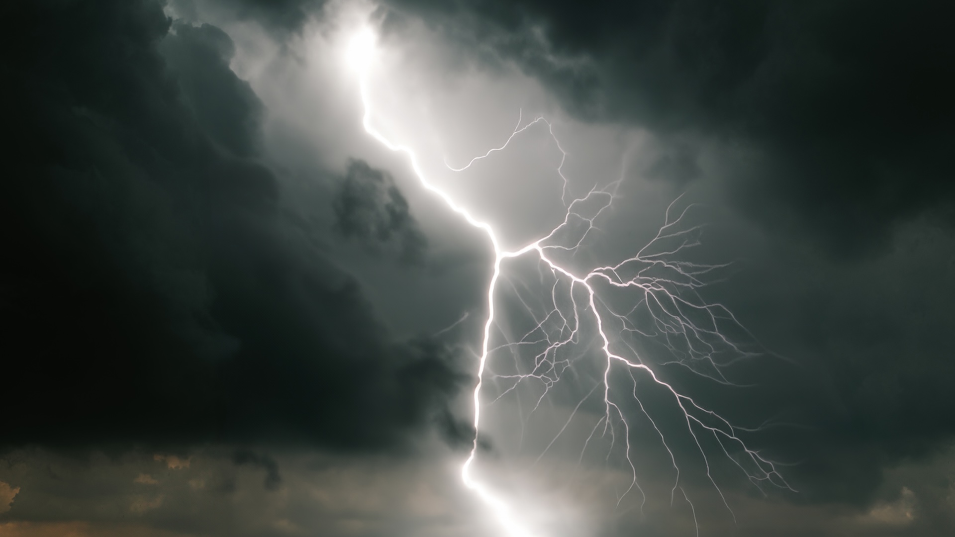 A dramatic scene of a bright lightning bolt cutting through dark storm clouds in the sky.