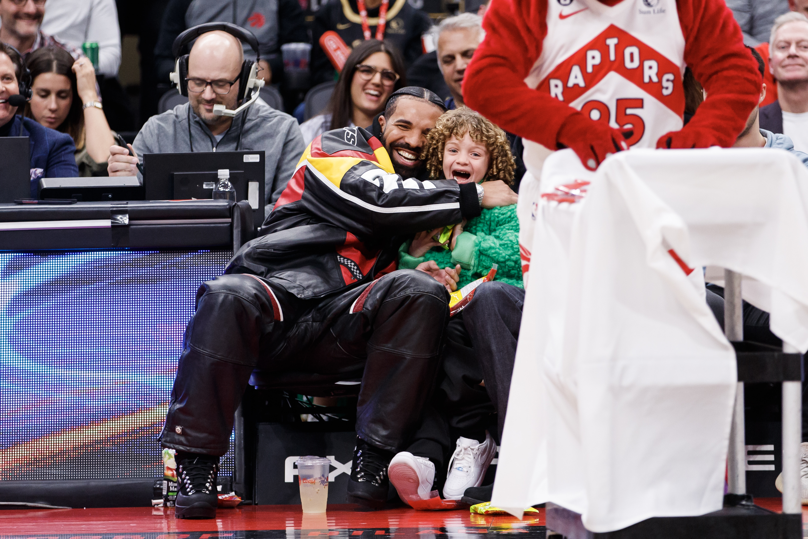 TORONTO, ON - DECEMBER 27: Rapper Drake embraces his son Adonis as the Raptor mascot brings over candy for him during the first half of the NBA game between the Toronto Raptors and the LA Clippers at Scotiabank Arena on December 27, 2022 in Toronto, Canada.