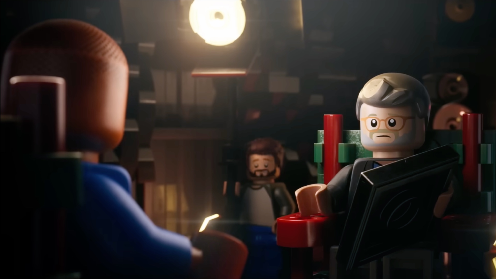 Pharrell Williams (left) and Morgan Neville (right) sit in film director chairs, talking to each other in the LEGO biopic movie Piece by Piece.