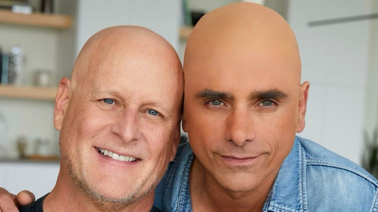 Dave Coulier and John Stamos posing closely in a bright indoor setting.