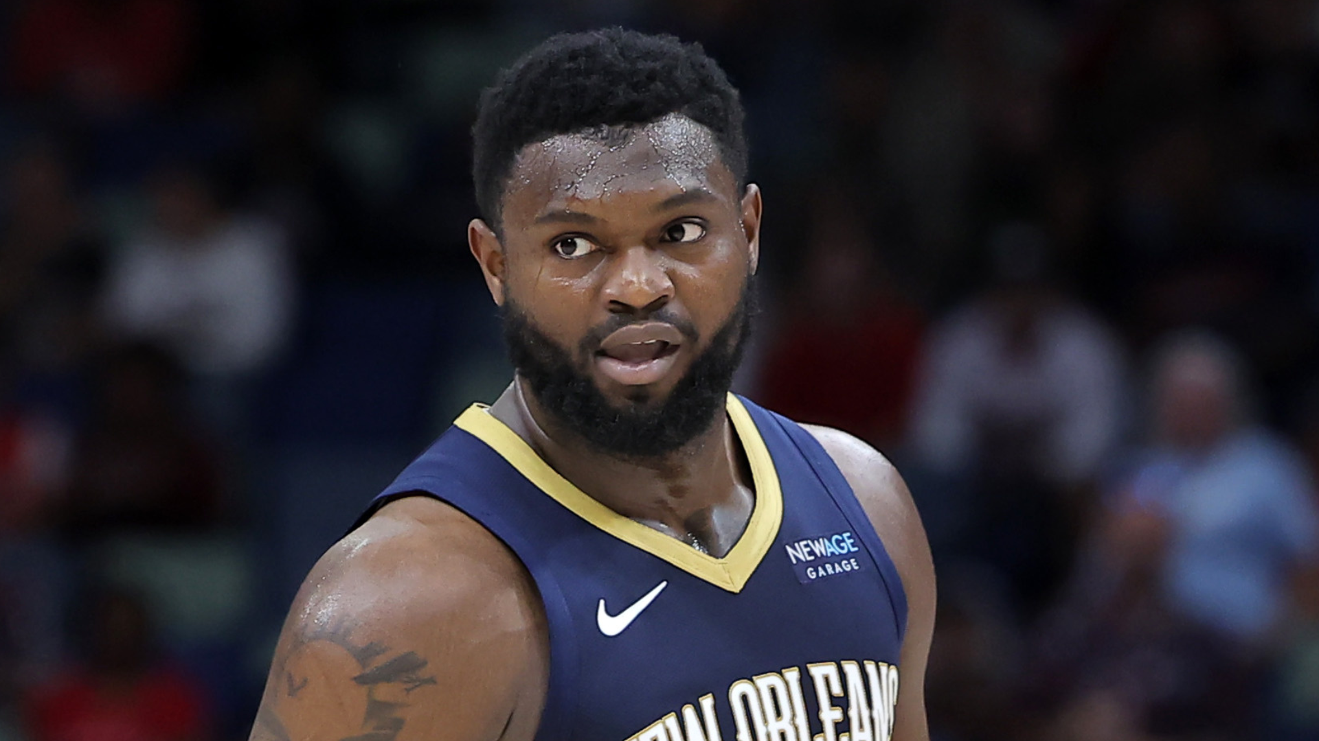 A basketball player in a New Orleans jersey on the court, looking to the side.