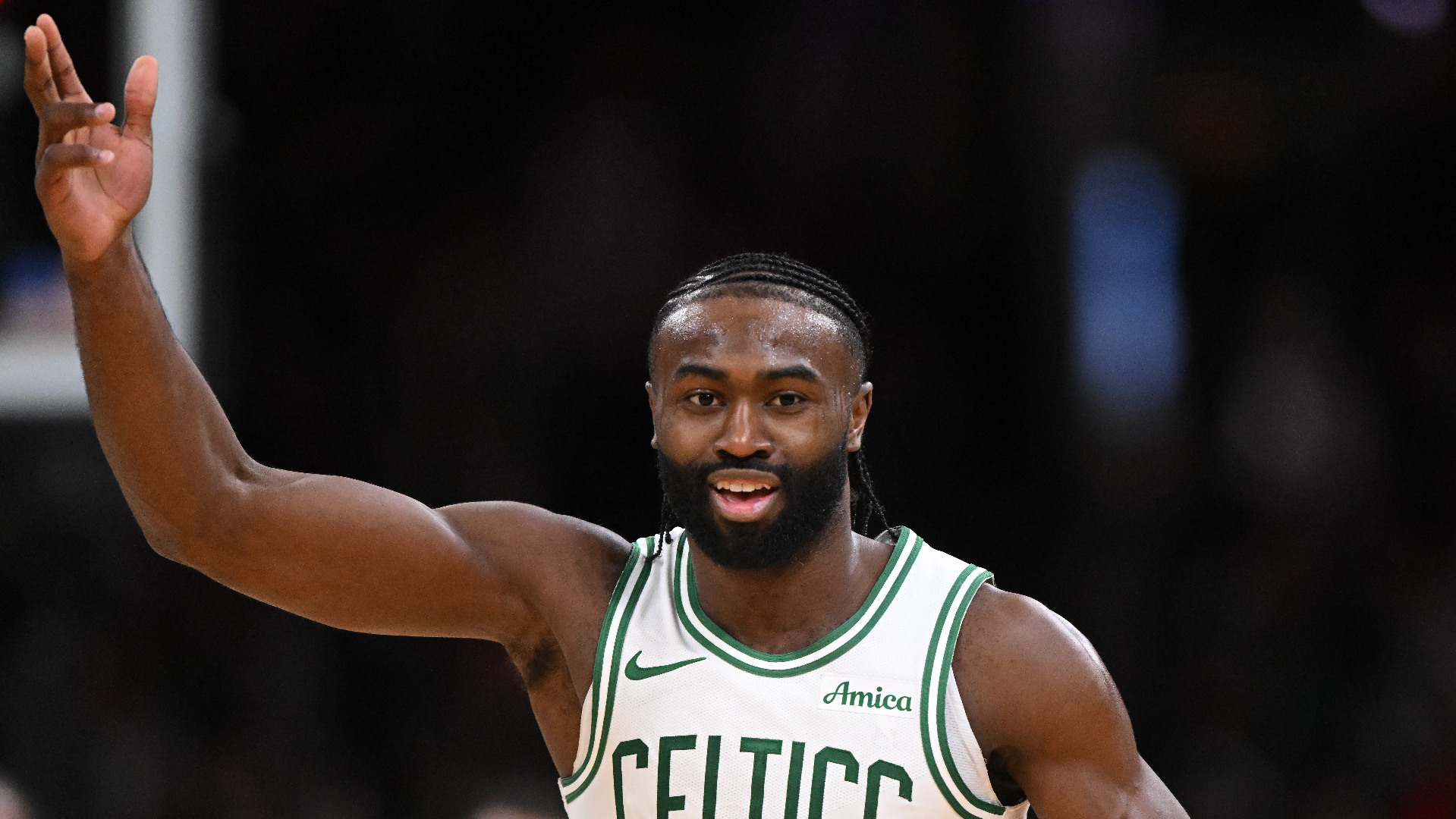 Jaylen Brown in a Boston Celtics jersey, mid-action on the court, raising one arm.