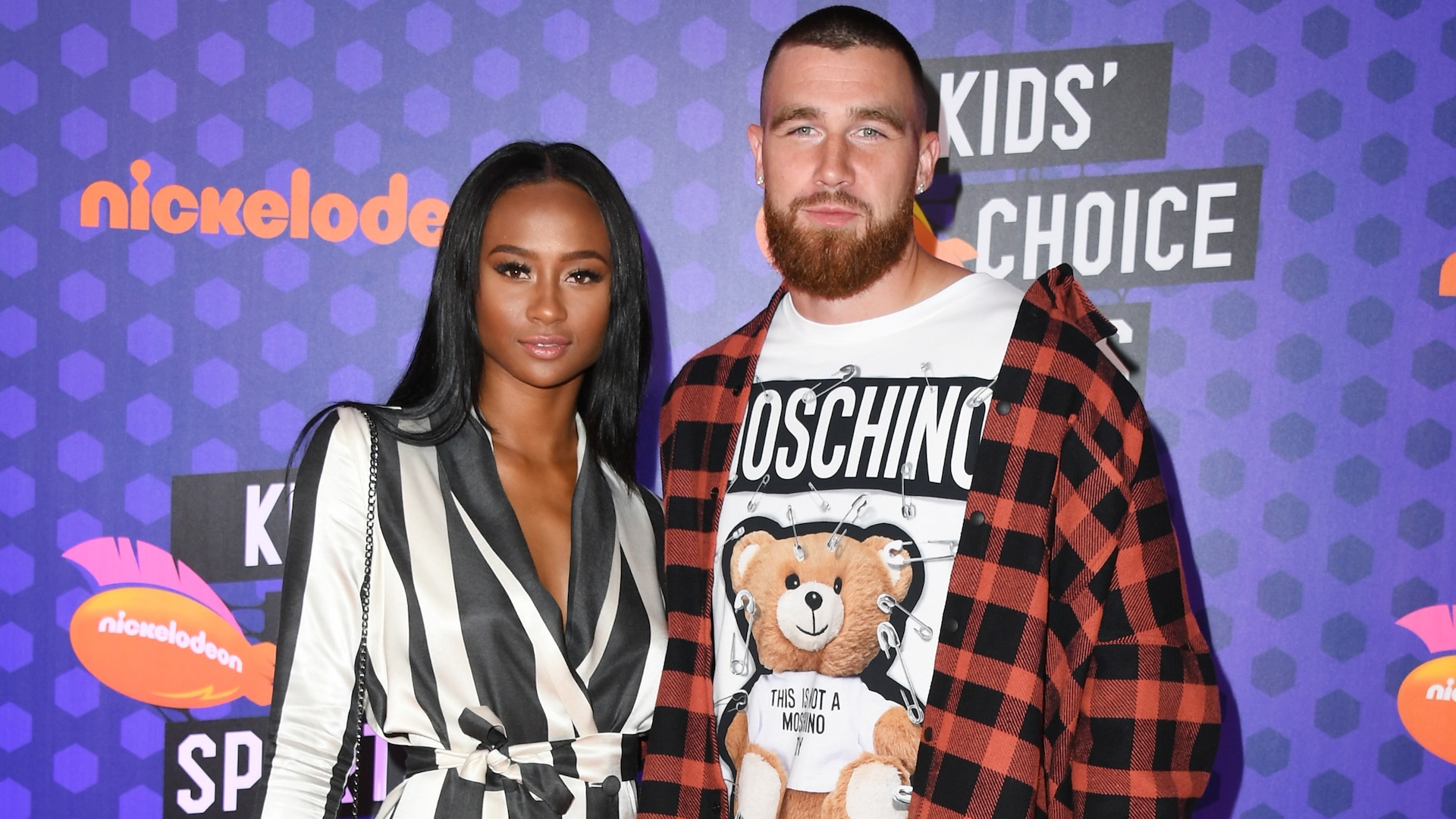 Kayla Nicole in a striped outfit and Travis Kelce in a Moschino shirt and plaid jacket at the Nickelodeon Kids' Choice Sports event.