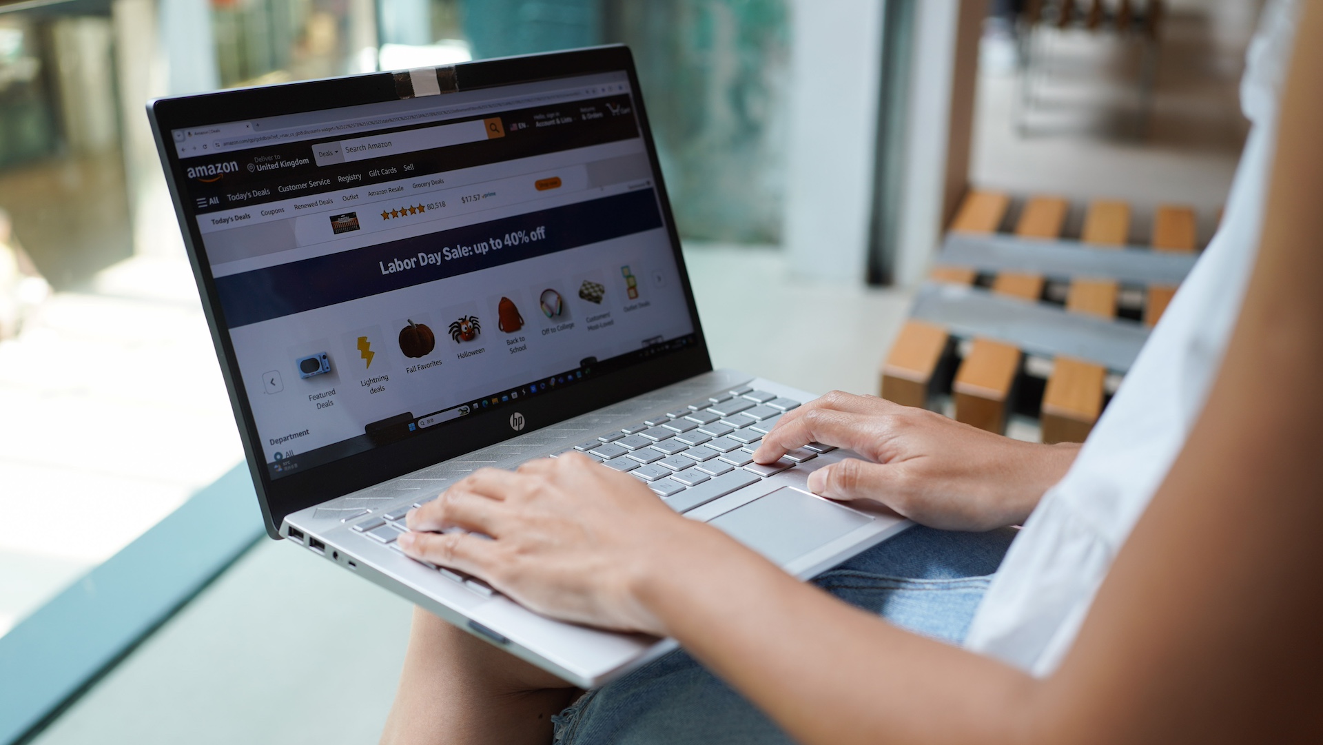 A person using a laptop to browse an online shopping website with a Labor Day sale banner.