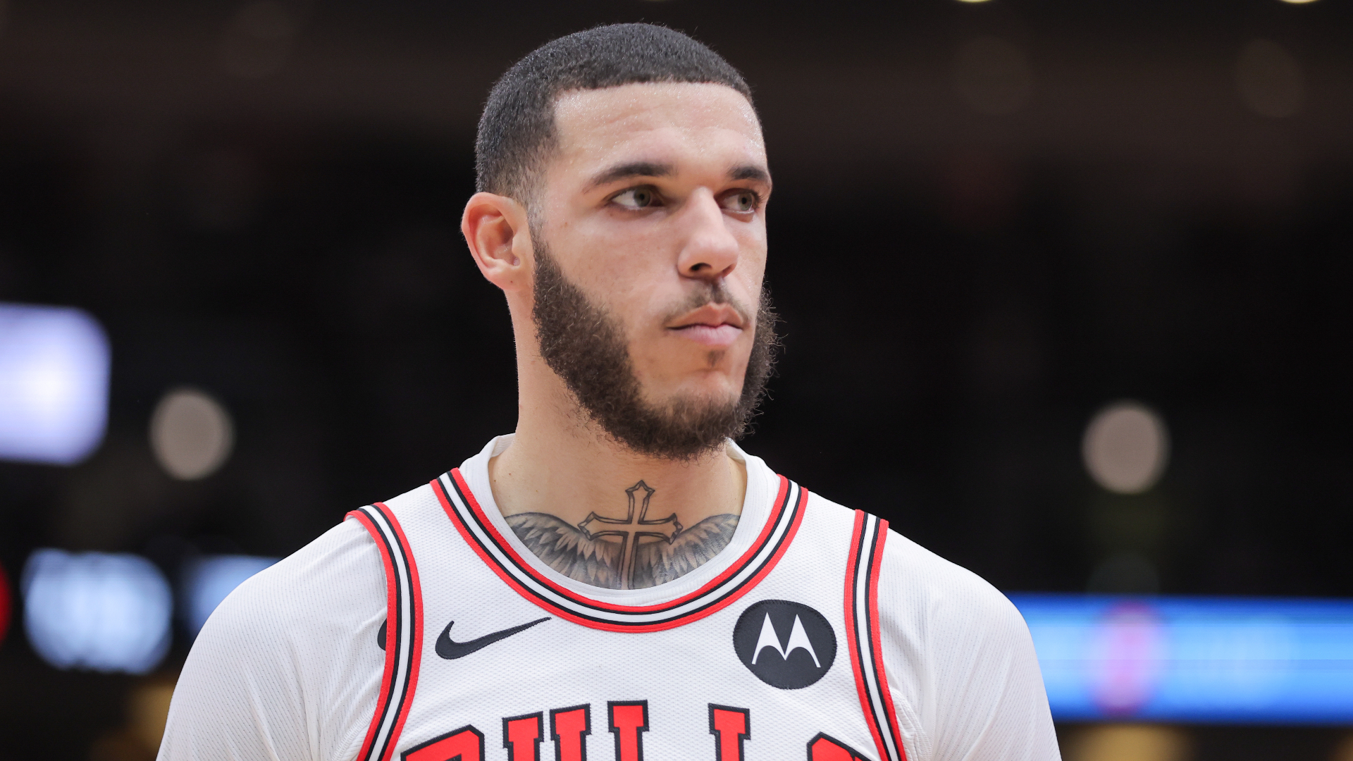Lonzo Ball in a Chicago Bulls jersey, looking to the side. He has short hair and a beard, with a tattoo on his neck.