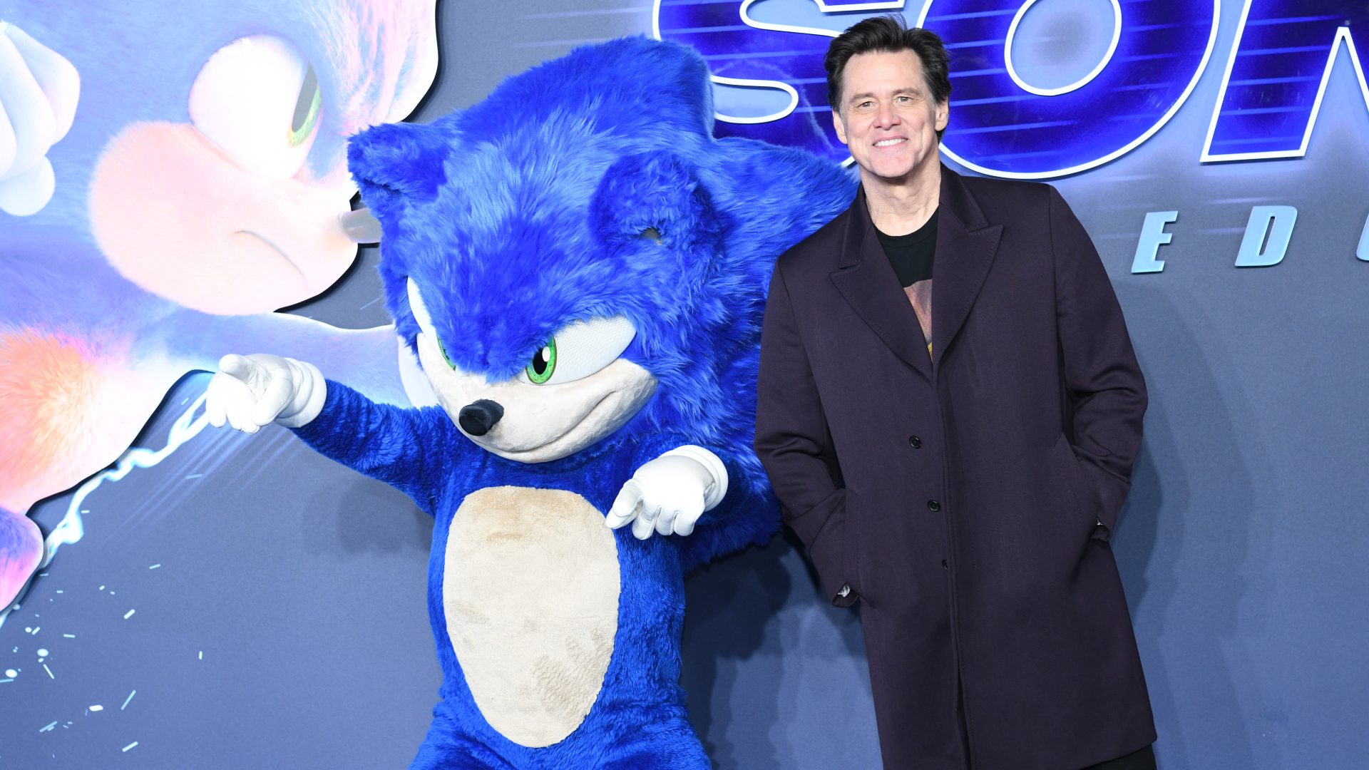 Jim Carrey poses with a person in a Sonic the Hedgehog costume at a movie premiere event.