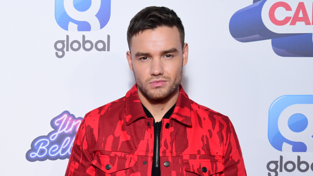 Liam Payne wearing a red jacket, posing.