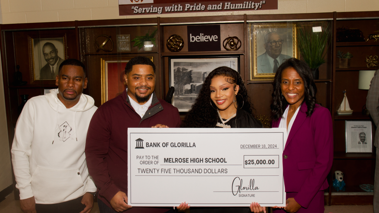 A group of four people, including GloRilla, holding a large check for $25,000 from "Bank of GloRilla" to Melrose High School.